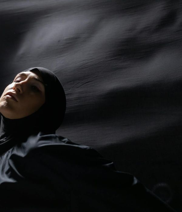 Woman performing a graceful yoga flow in a dark studio.